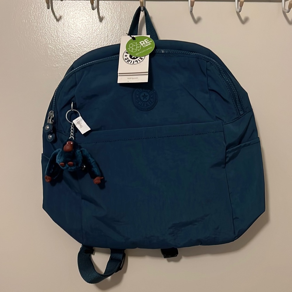 Midnight teal Kipling backpack with monkey keychain “Winston” attached.